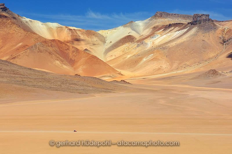 Jeep driving on the Altiplano of Bolivia in front of colorful mountains